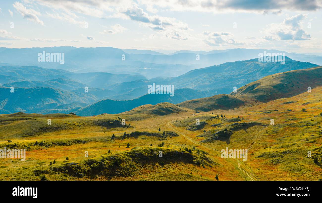 Wide mountain view with sun rays spreading through clouds and valleys Stock Photo