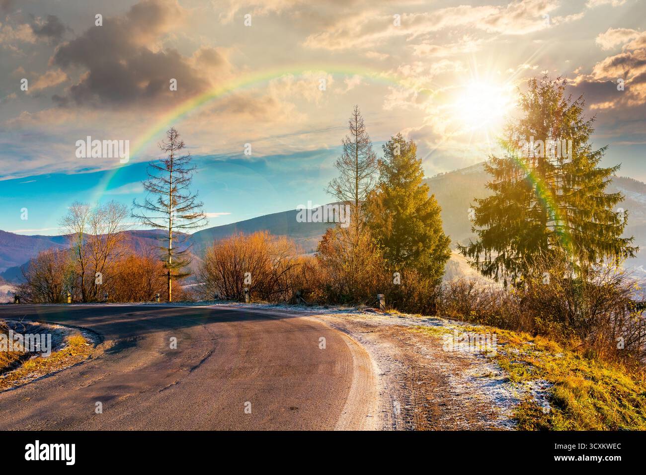country road in mountains at sunset. beautiful countryside landscape in late autumn. fir trees on the roadside in evening light. scenic view of blue s Stock Photo