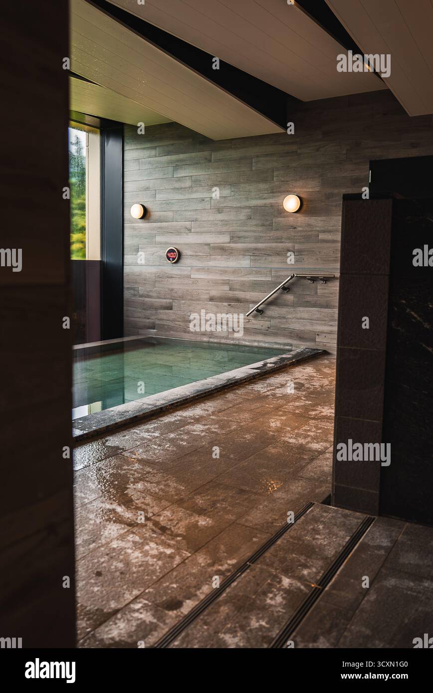 Indoor onsen style bath with rectangular pool and warm wall lights Stock Photo