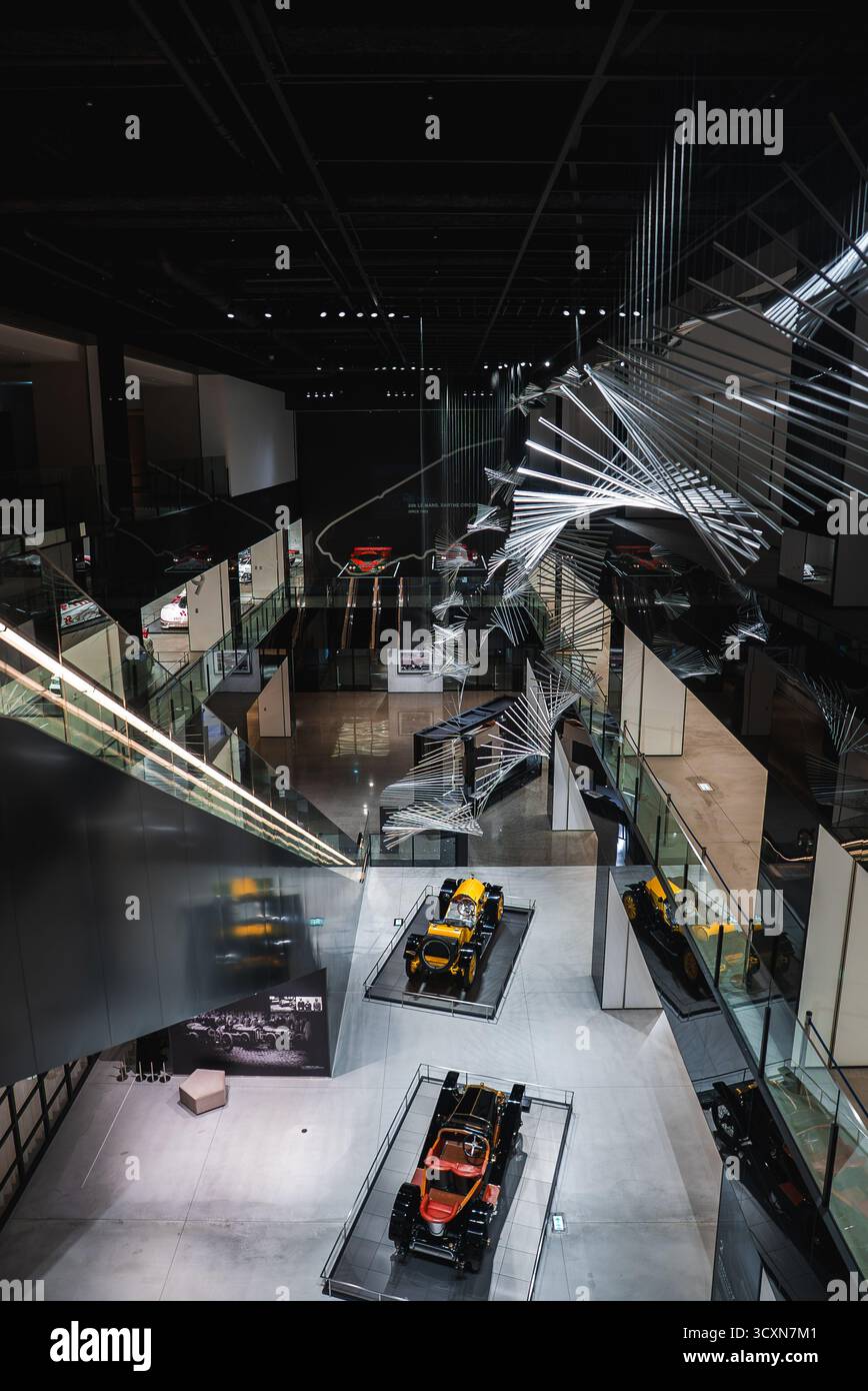 Multi level museum interior with race cars under metallic sculptures ...