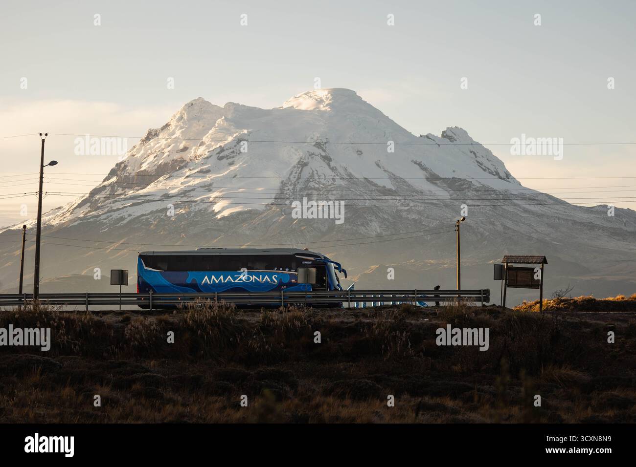 Amazonas interprovincial bus passing near Antisana Volcano at sunrise, in the Ecuadorian Andes, South America. Stock Photo