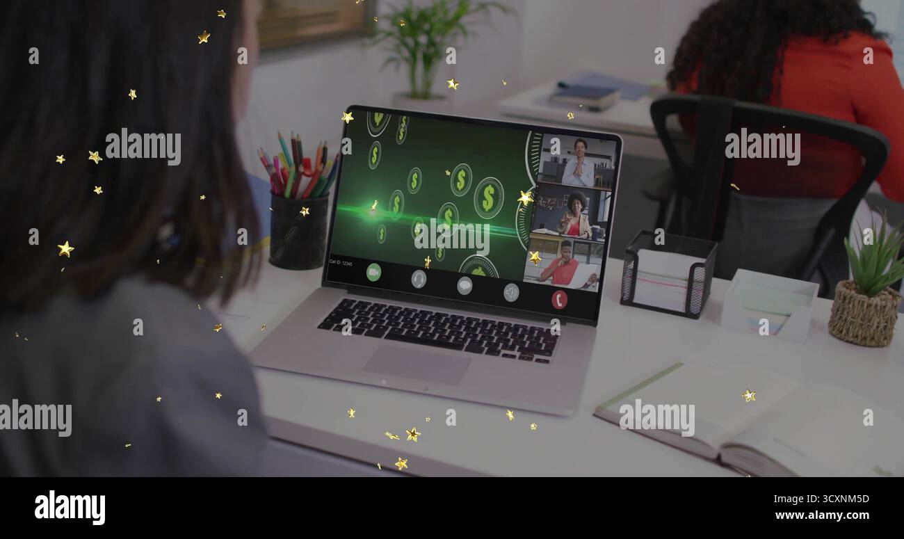 Displaying silver laptop showing split-screen meeting at office desk, with digital currency icons Stock Photo