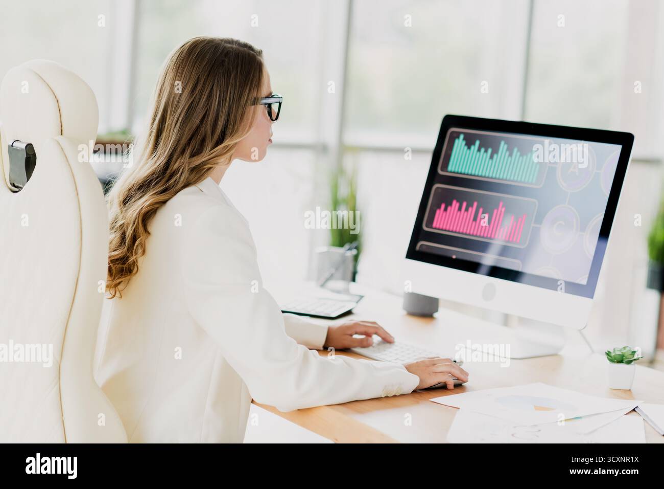 Businesswoman Analyzing Data on a Computer in a Modern Office Setting, Emphasizing Financial and Professional Tasks in a Stylish Interior Stock Photo