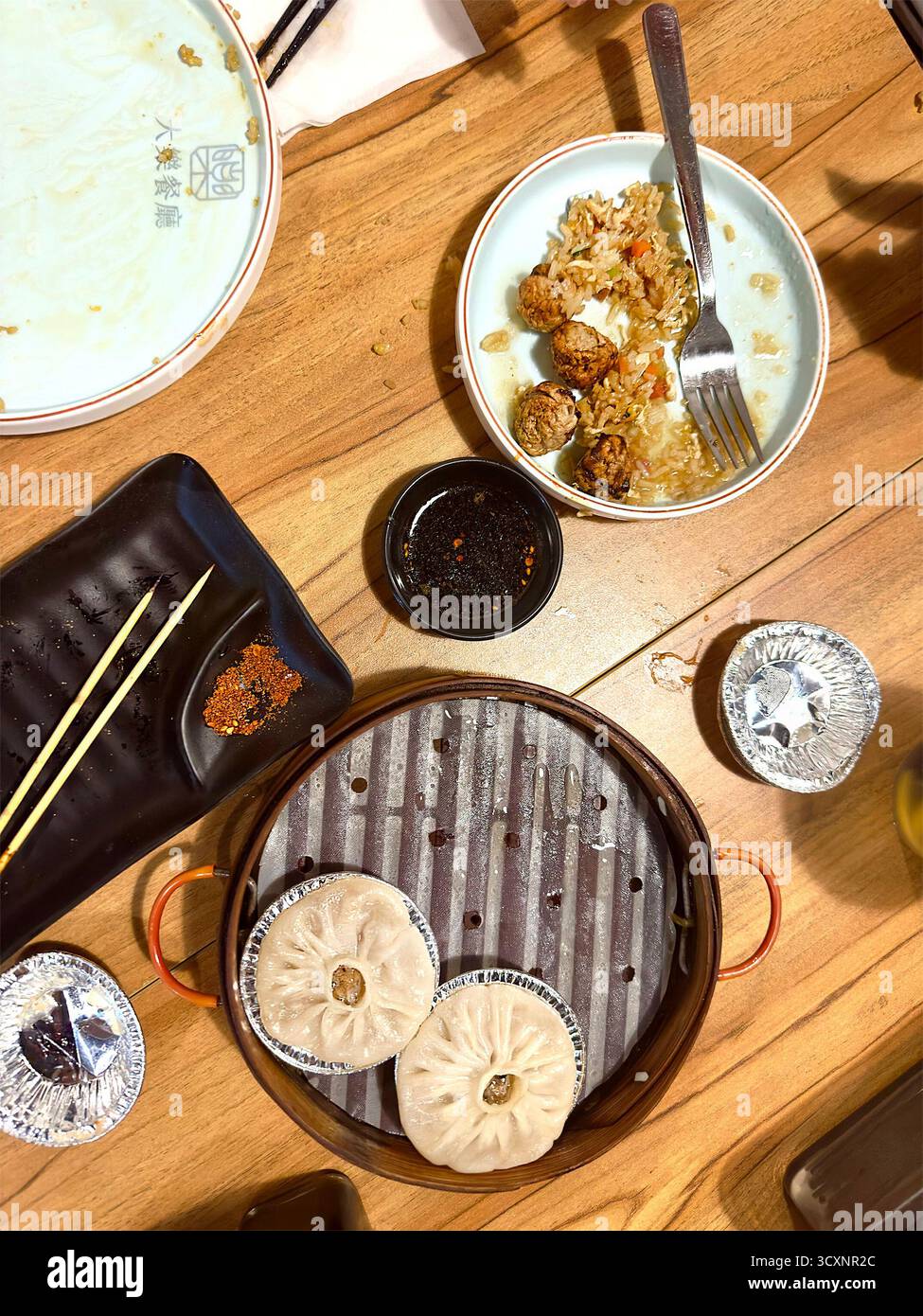 Top view of a rustic table setting with traditional Chinese dim sum, dipping sauces, and chopsticks in a casual dining setup asian dumplings - Smartphone Captured Stock Image