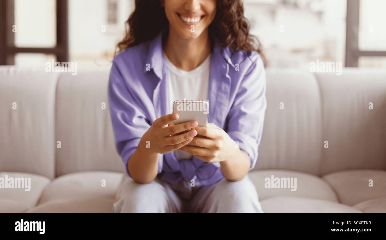 Woman Using Smartphone While Relaxing on a Comfortable Couch at Home Stock Photo