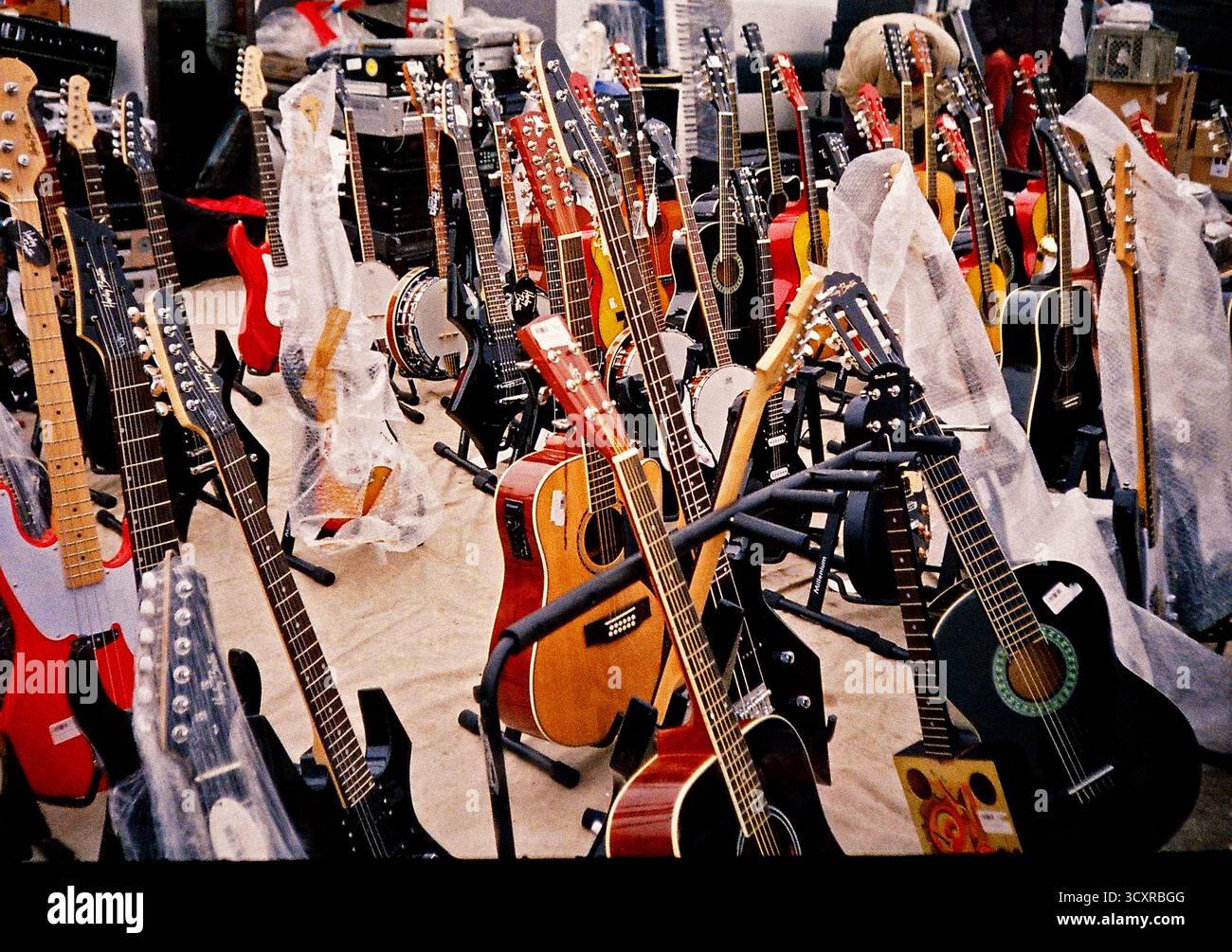 Market stall filled with acoustic guitars displayed outdoors, creating a colorful everyday scene captured with an authentic analog film aesthetic. Stock Photo