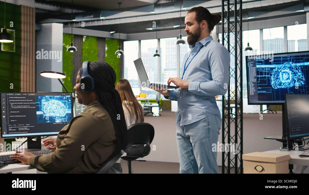 Team of programmers in office developing software applications, integrating AI driven automation in operations. Developers at work debugging applications to resolve issues, camera A Stock Photo