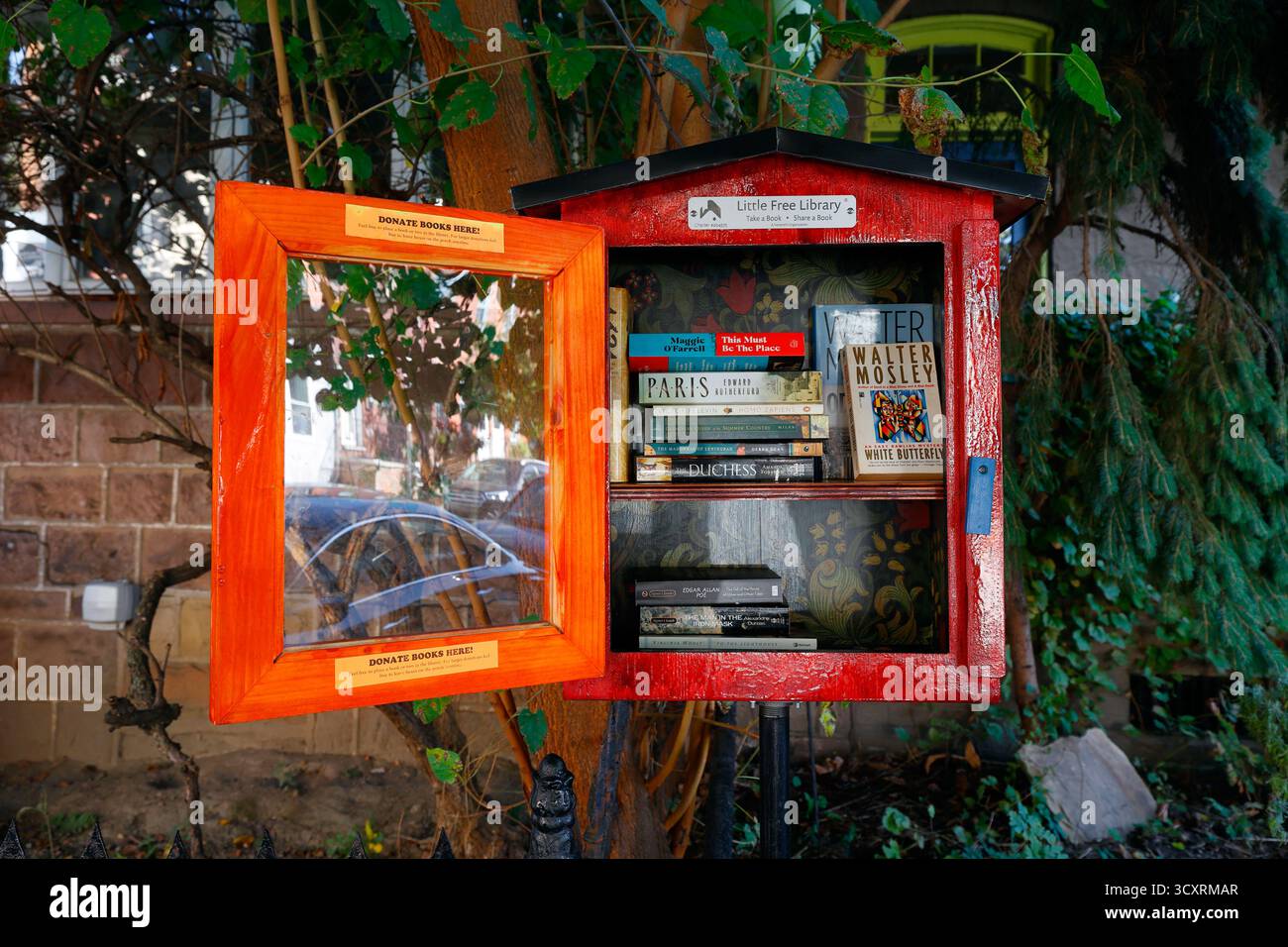 A Little Free Library book sharing box containing books of fiction. Stock Photo