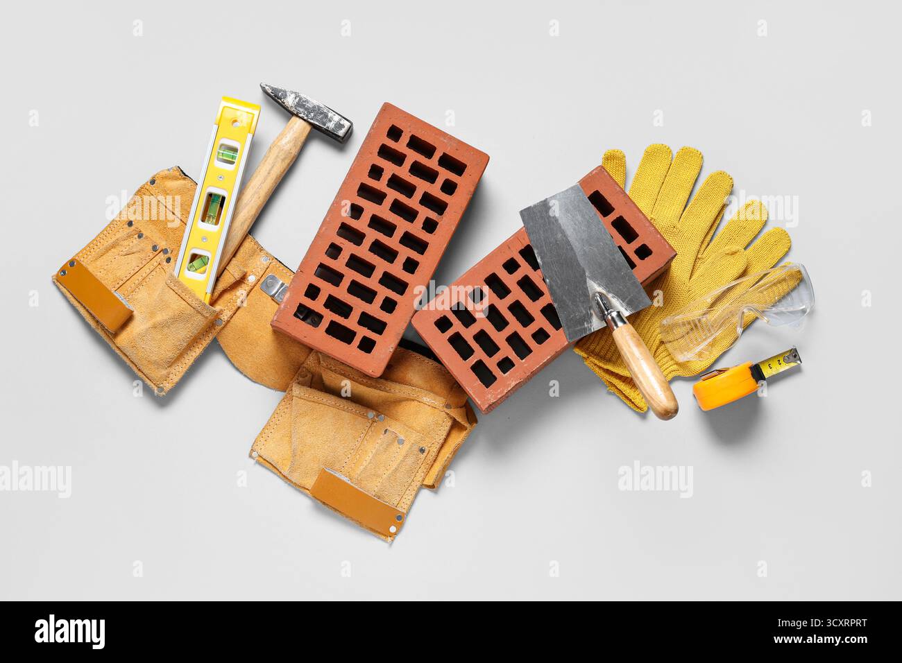 Bricks with builder belt and different tools on white background Stock Photo