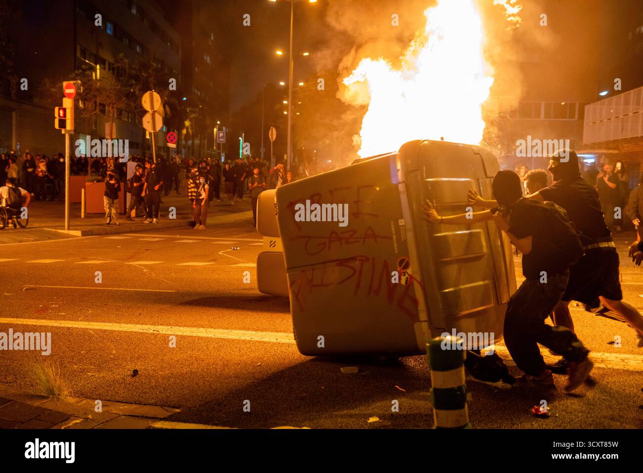Barcelona, Spain. 15th Oct, 2025. Protesters push a burning container ...