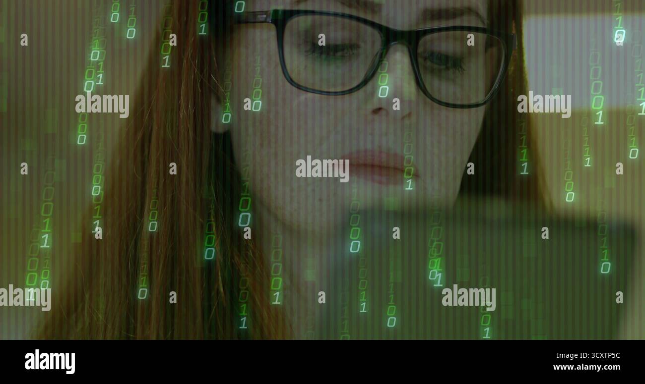 Gazing female developer wearing eyeglasses analyzing code on laptop in study, with binary overlay Stock Photo