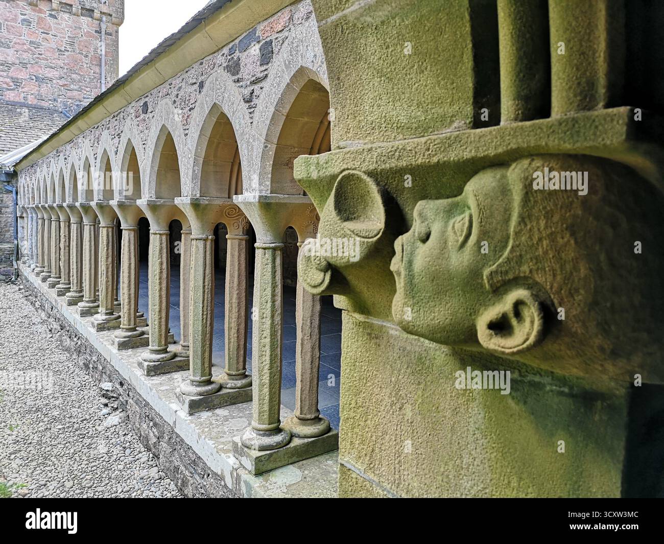 Head and wine cup carving and cloister pillars, Iona Abbey on Iona, Isle of Mull – medieval Christian symbolism in sacred Inner Hebrides architecture. - Smartphone Captured Stock Image