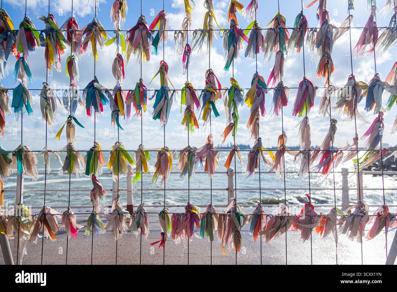 Multi-colored ribbons tied to a steel lattice overlooking the sea on a sunny day Stock Photo