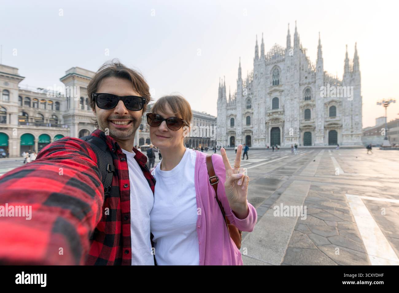 Happy couple taking selfie in front of Duomo cathedral in Milan, Lombardia - Two tourists having fun on summer vacation in Italy Stock Photo