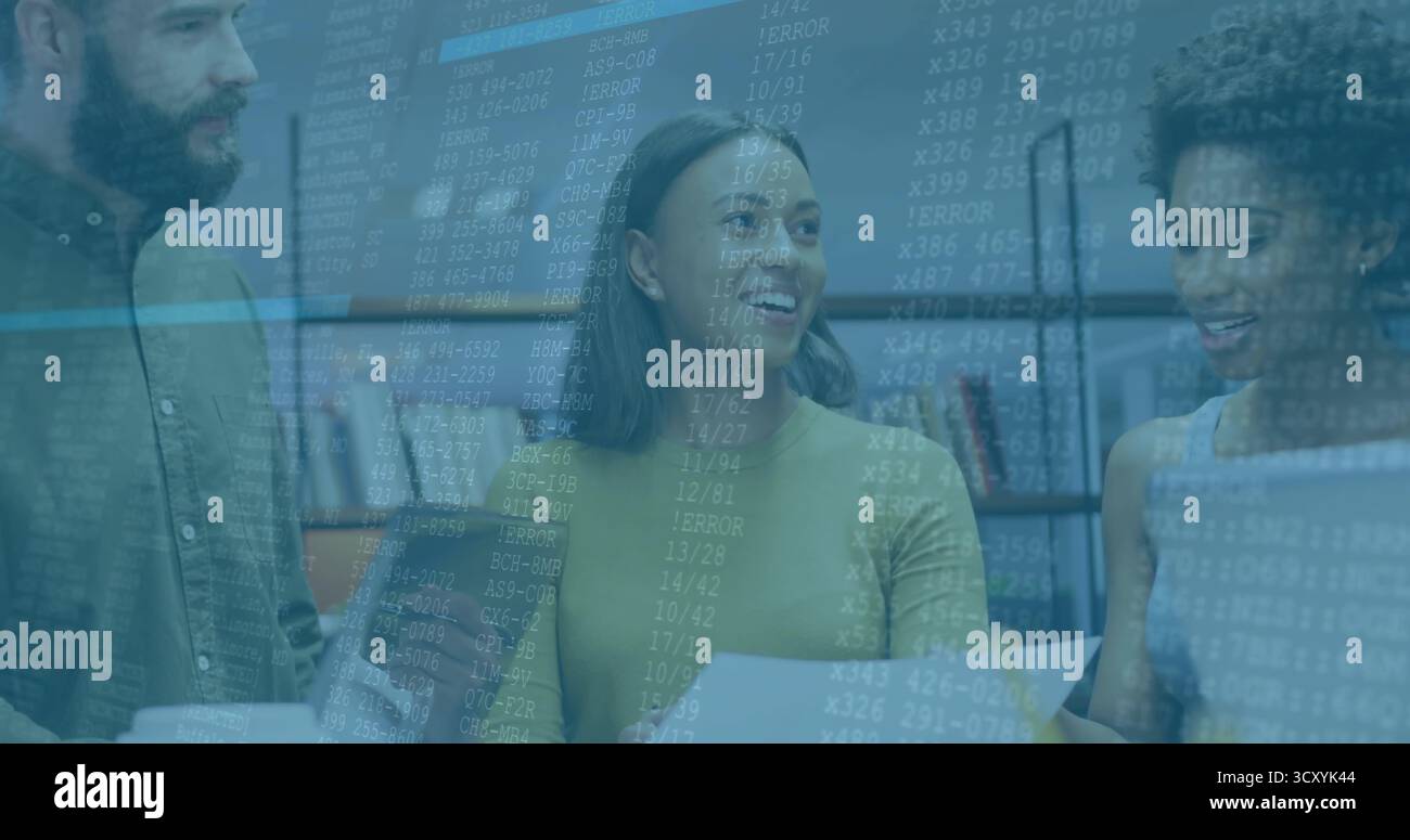 Three software developers reviewing code printout and laptop screen in office, with bookshelves Stock Photo