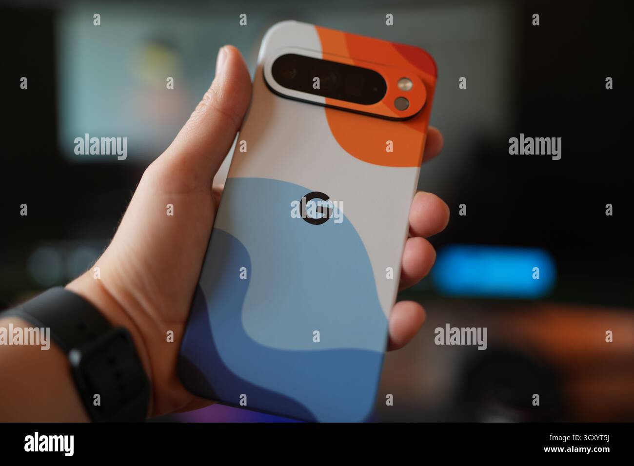 Colorful smartphone case held in hand with blurred background in indoor setting Stock Photo