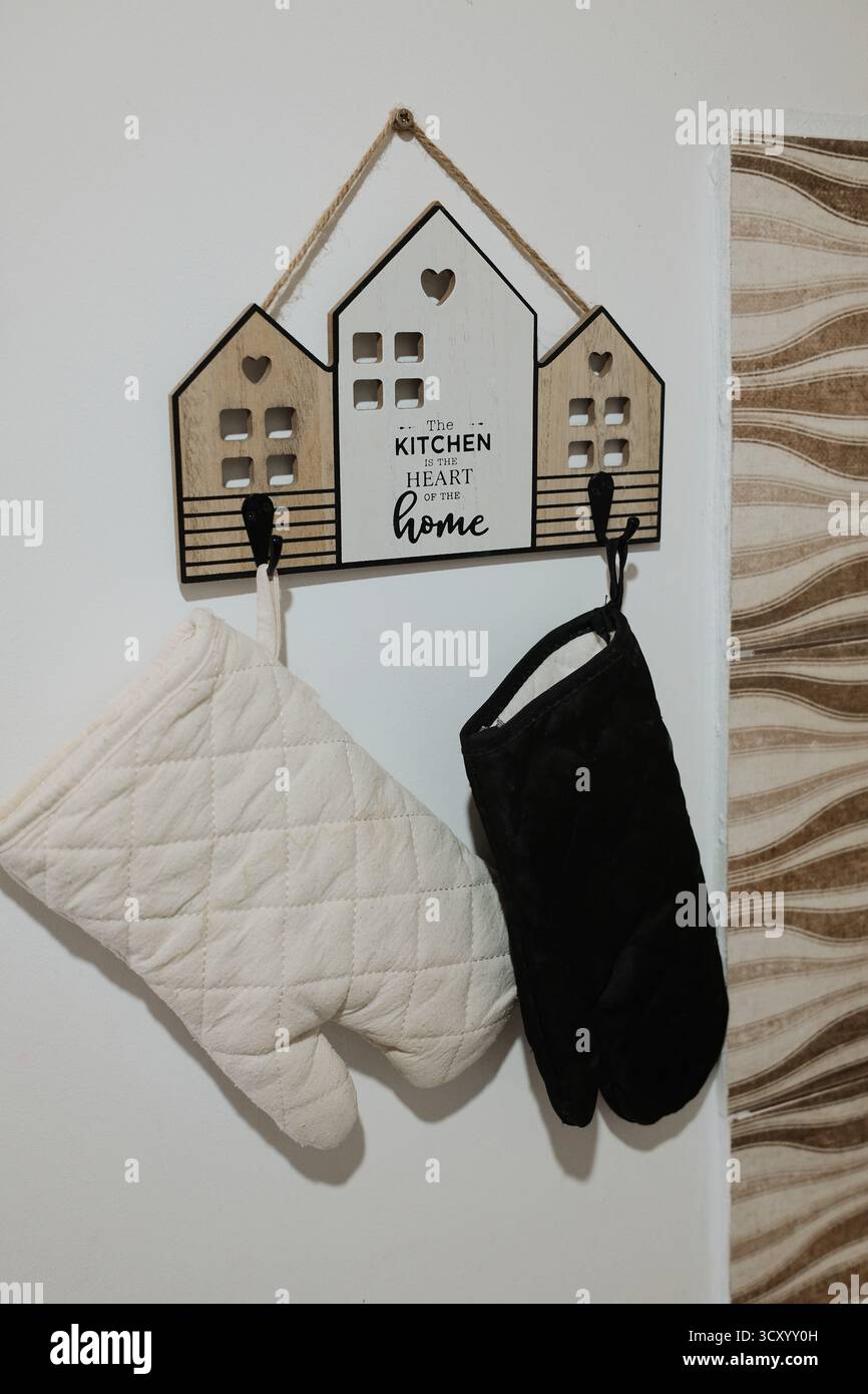 Decorative kitchen wall hanger shaped like houses with oven mitts. Cozy rustic detail ideal for home decor, cooking, or lifestyle projects. Stock Photo
