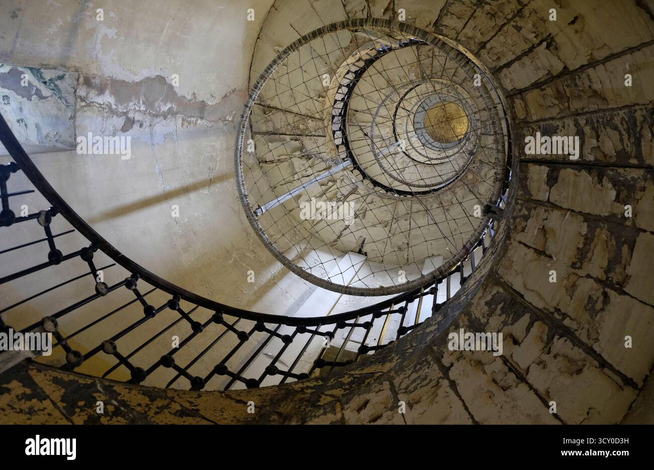 Looking vertically up a decrepit old wrought iron spiral staircase in the Phare de Calais, an prominent old lighthouse now monument Stock Photo