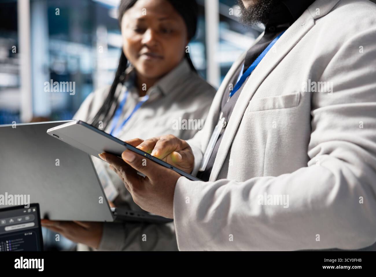 Close up of developers in data center using tablet to update infrastructure software, configuring network virtualization. Server hub IT professionals using device to verify hardware settings Stock Photo