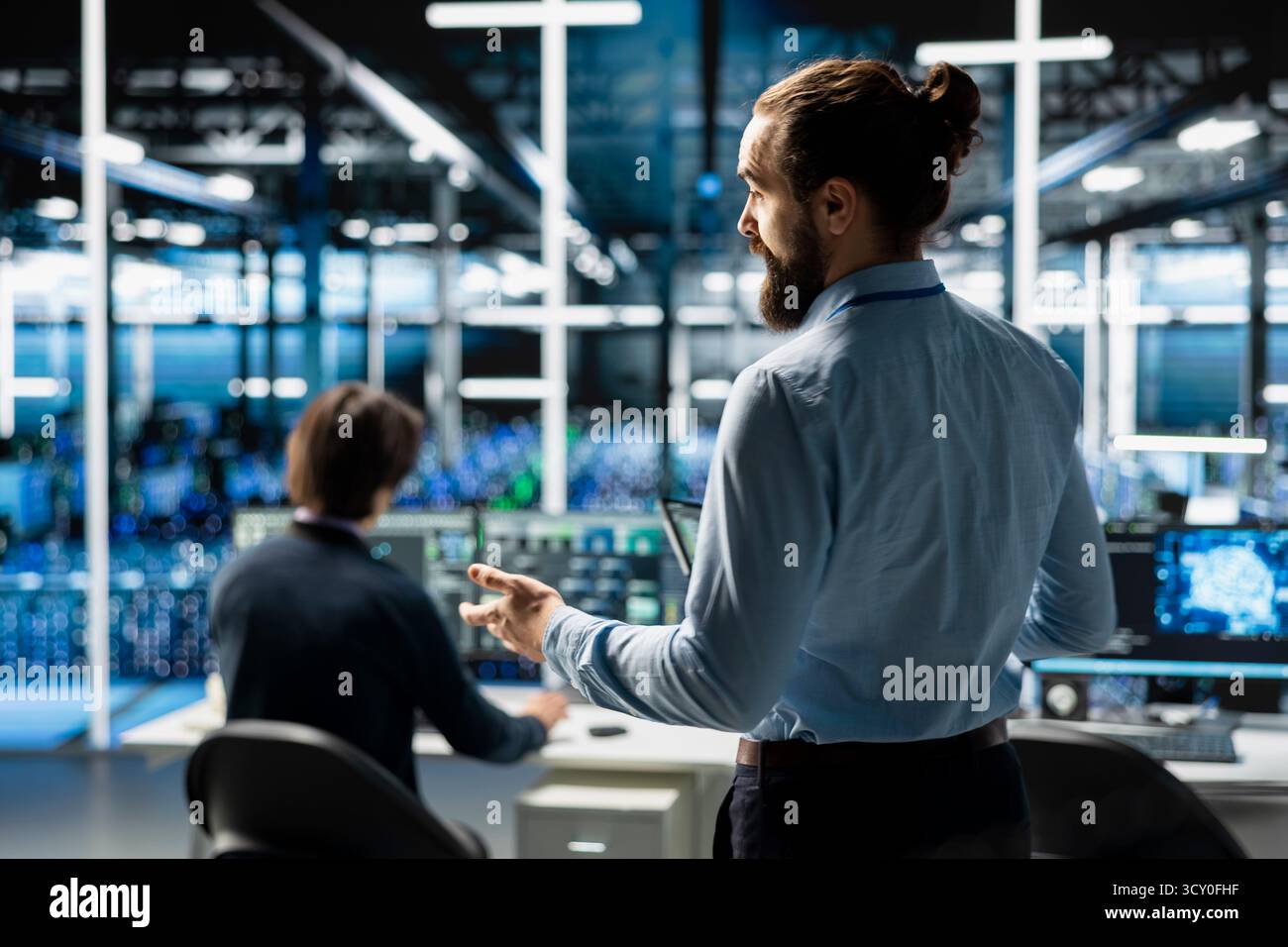 Teamworking admins coding in data center, updating AI driven automation scripts. Server room colleagues programming artificial intelligence algorithms, debugging infrastructure Stock Photo
