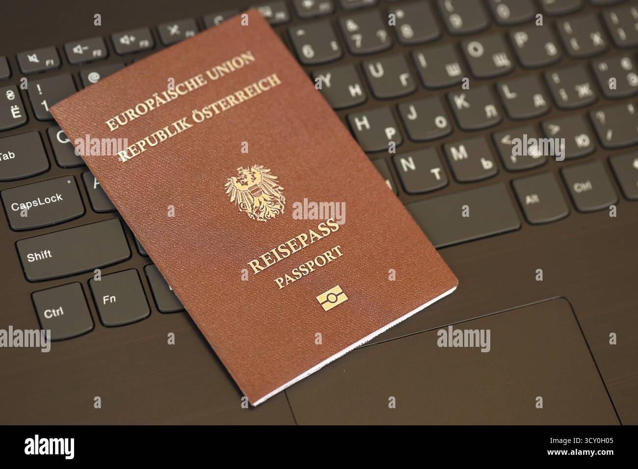 Austria passport lies on black laptop keyboard buttons background close up. Technologies and control in Europe concept Stock Photo