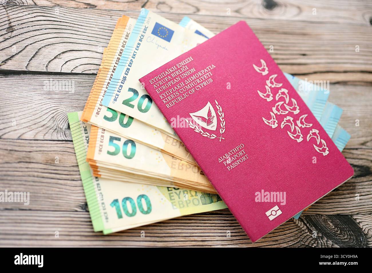 Kyprus passport lies with euro money banknotes on wooden background close up. Cash and payments in Europe concept Stock Photo