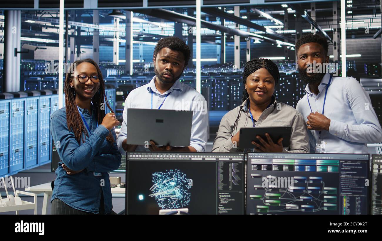 Portrait of smiling data center specialists collaborating in server facility, using node tree software to analyze datasets. Happy team using visual programming to improve gear performance, camera A Stock Photo