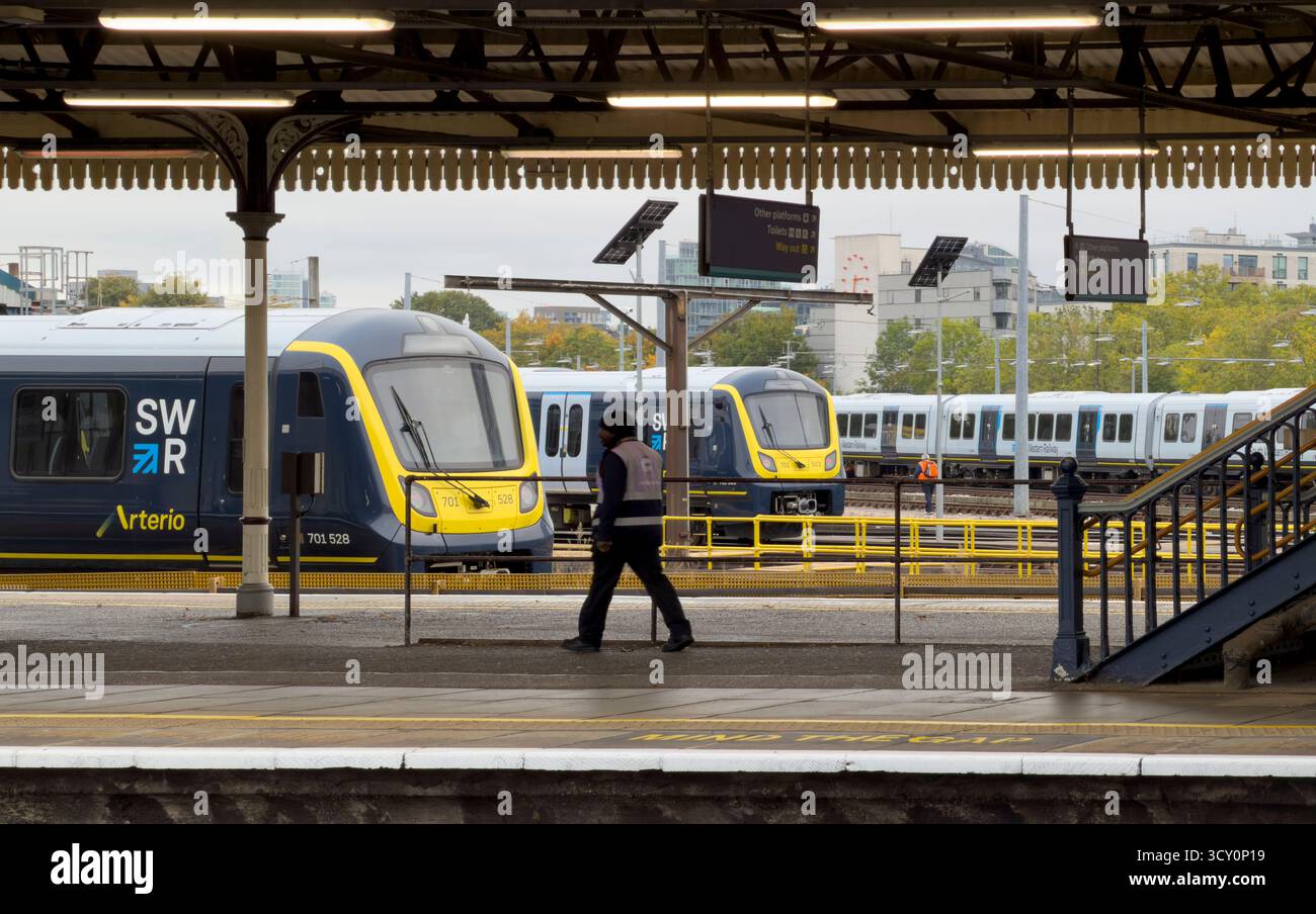 A worker walks at London Clapham Junction station, a major hub for South Western Railway, as trains prepare for departure. Stock Photo