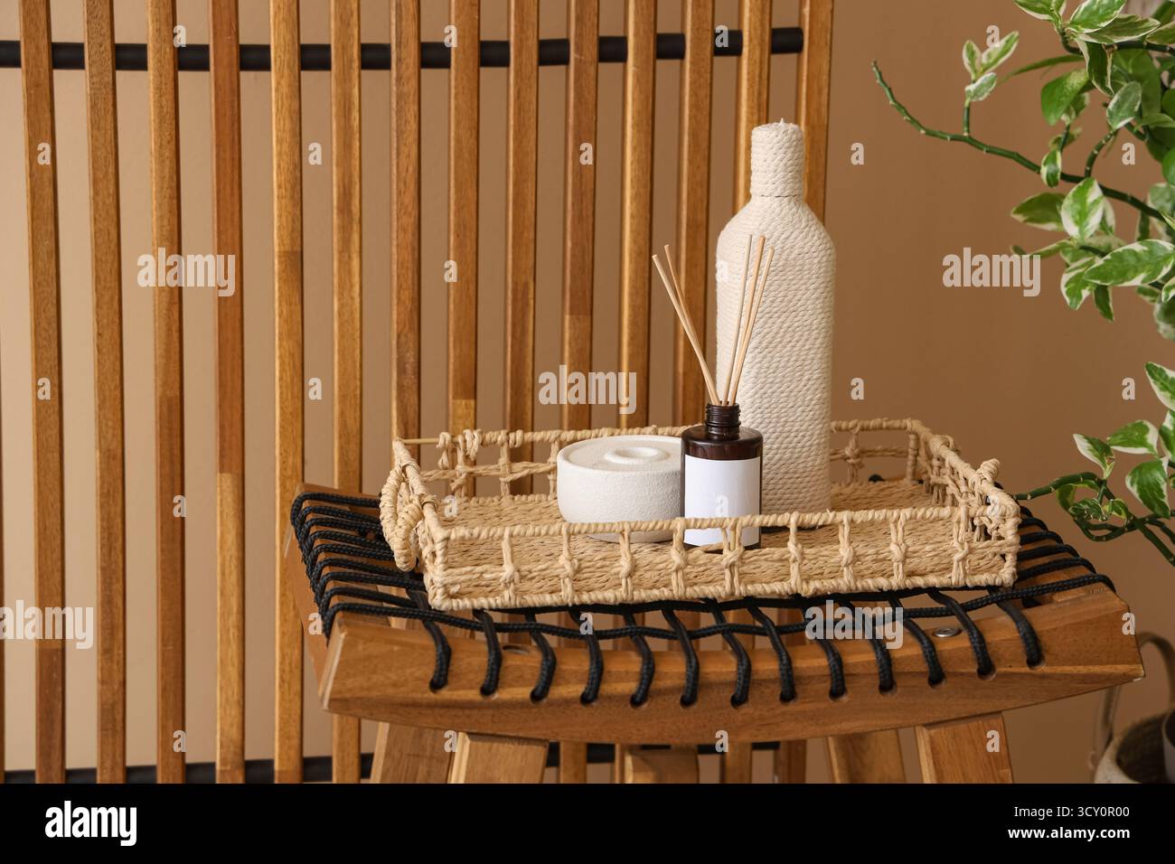 Wooden folding screen, table with candle and reed diffuser near beige ...