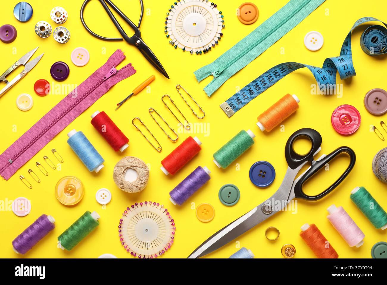 Composition with different thread spools and sewing accessories on yellow background Stock Photo