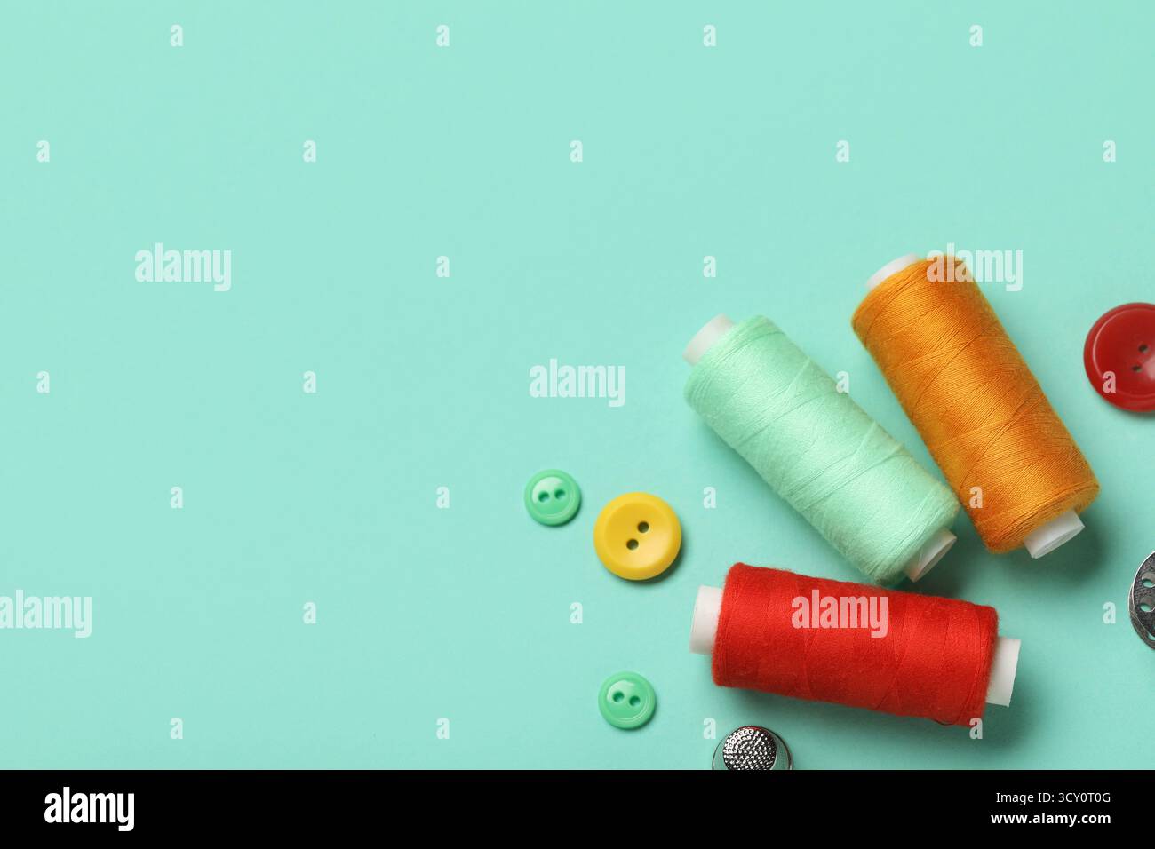 Composition with thread spools and buttons on mint background, closeup Stock Photo