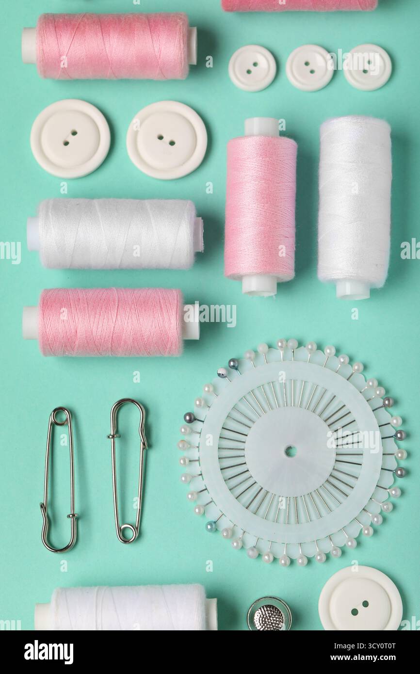 Composition with thread spools, ball pins and buttons on mint background, closeup Stock Photo