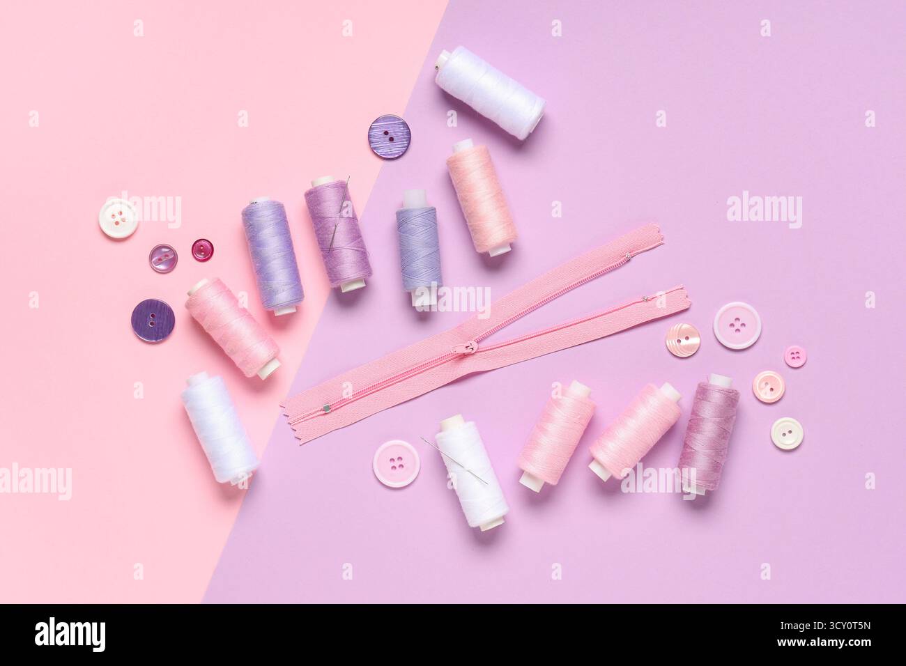Thread spools with buttons and zipper on color background Stock Photo