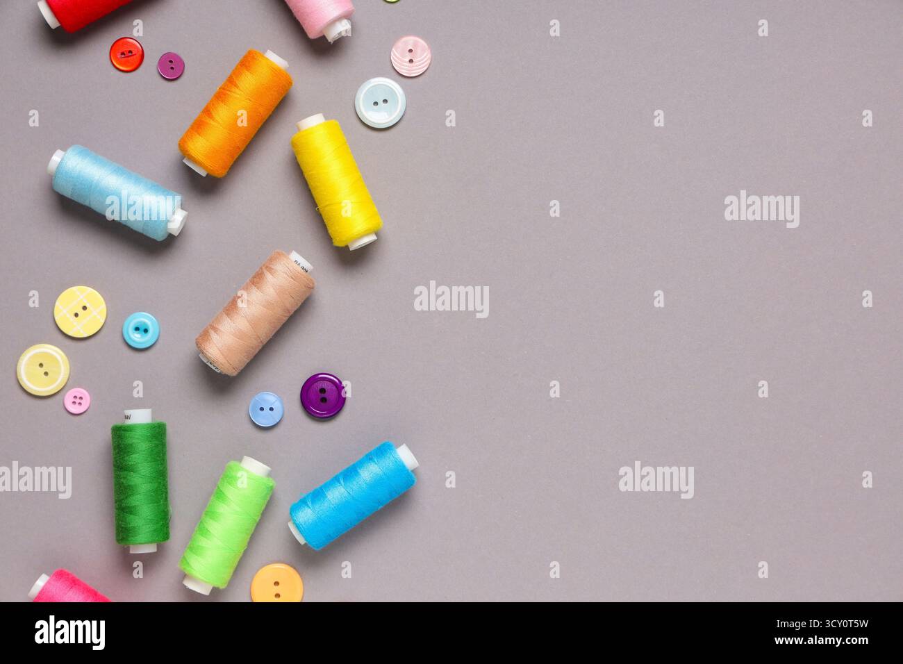 Different thread spools and buttons on grey background Stock Photo