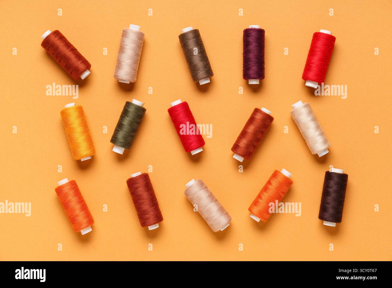 Many different thread spools on orange background Stock Photo