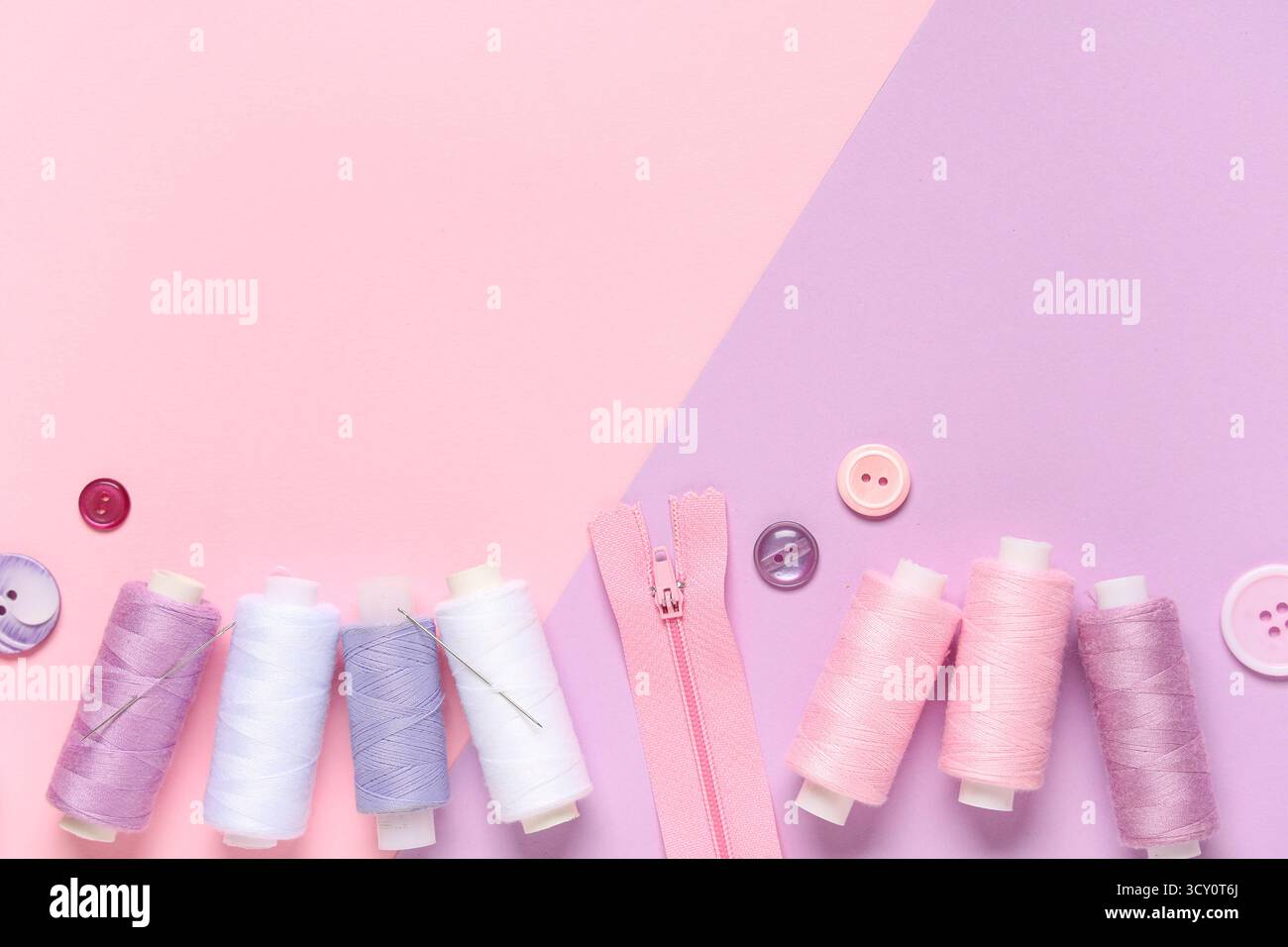 Thread spools with buttons and zipper on color background Stock Photo