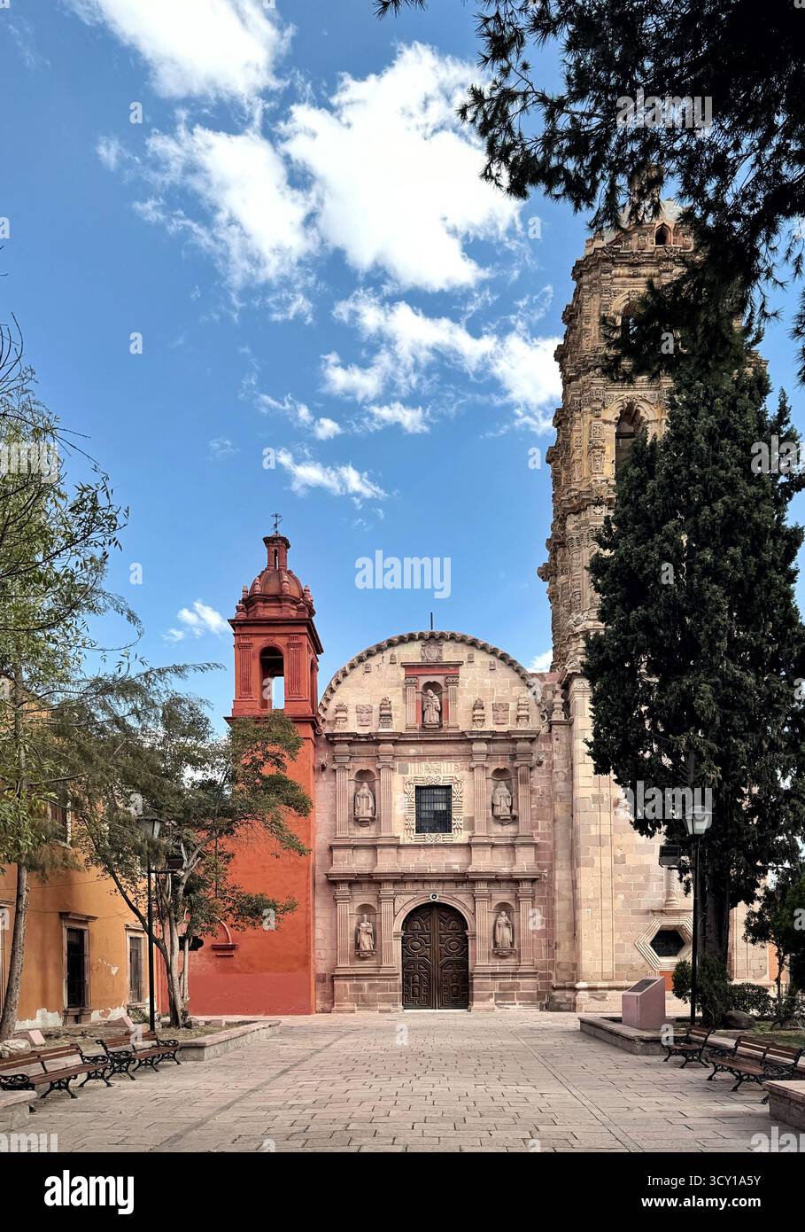 Historic Templo de San Agustín church in San Luis Potosi, Mexico, with ornate facade and bell tower i surrounded by trees and benches - Smartphone Captured Stock Image