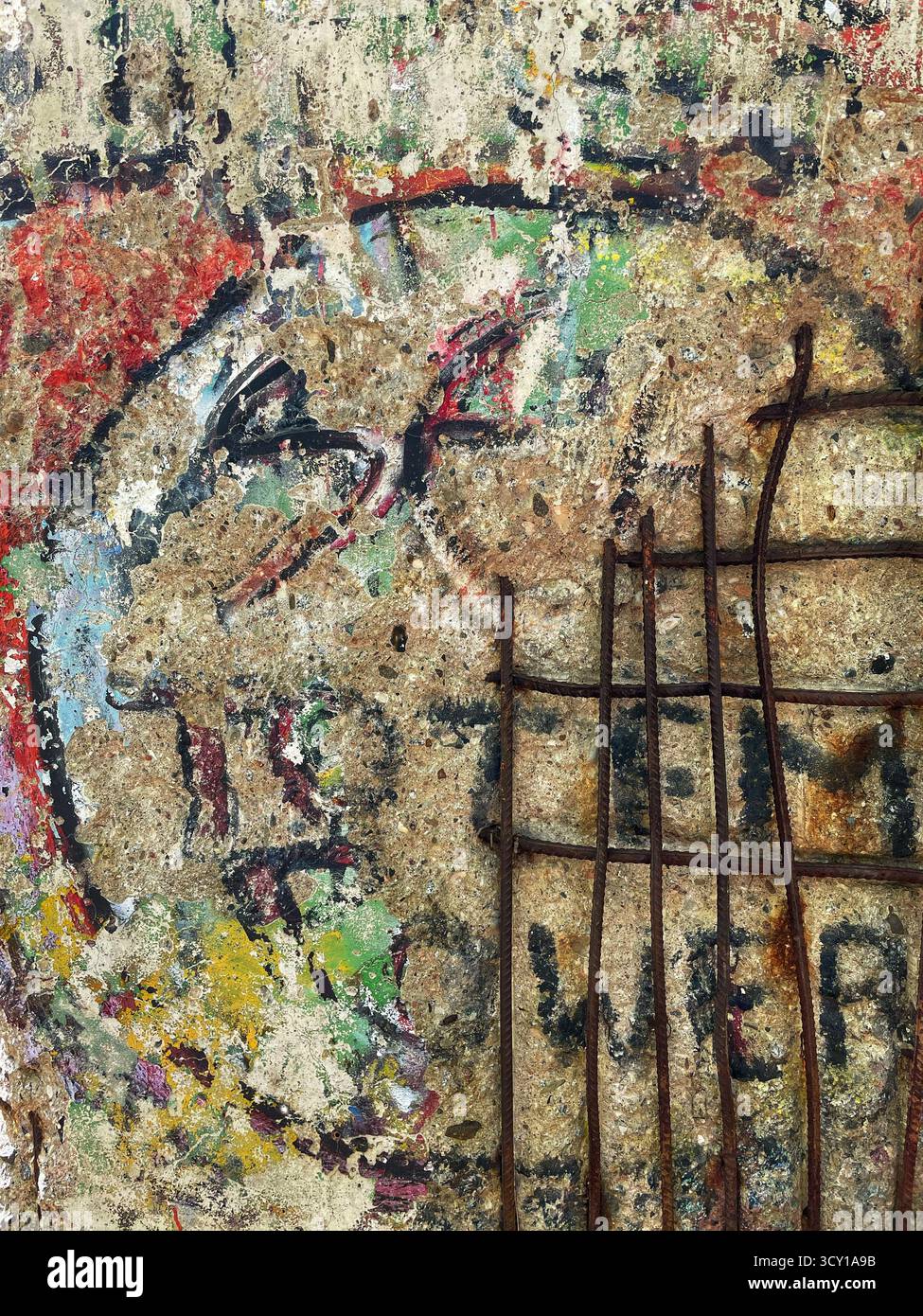 Close-up of a weathered graffiti wall with rusted metal bars, showcasing vibrant colors and aged textures in urban decay Stock Photo