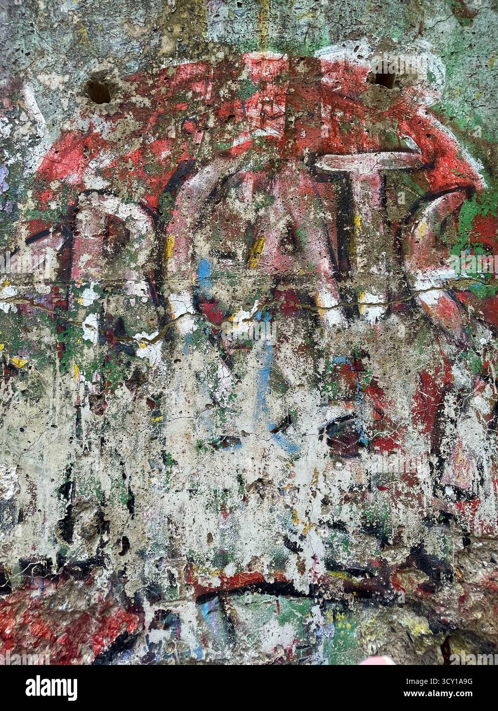 Close-up of abstract, weathered graffiti art on a concrete surface with colorful layers of peeling paint. - Smartphone Captured Stock Image