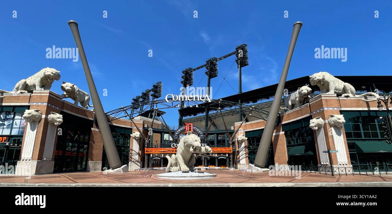 Wide-angle view of Comerica Park entrance with iconic tiger sculptures and towering decorative bats beneath a clear blue sky - Smartphone Captured Stock Image