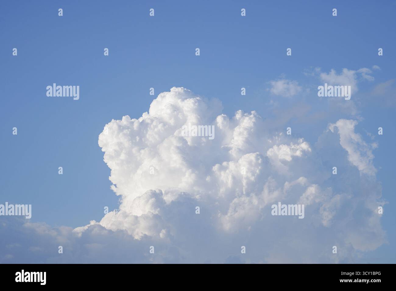 A large, fluffy white cloud against a clear blue sky Stock Photo