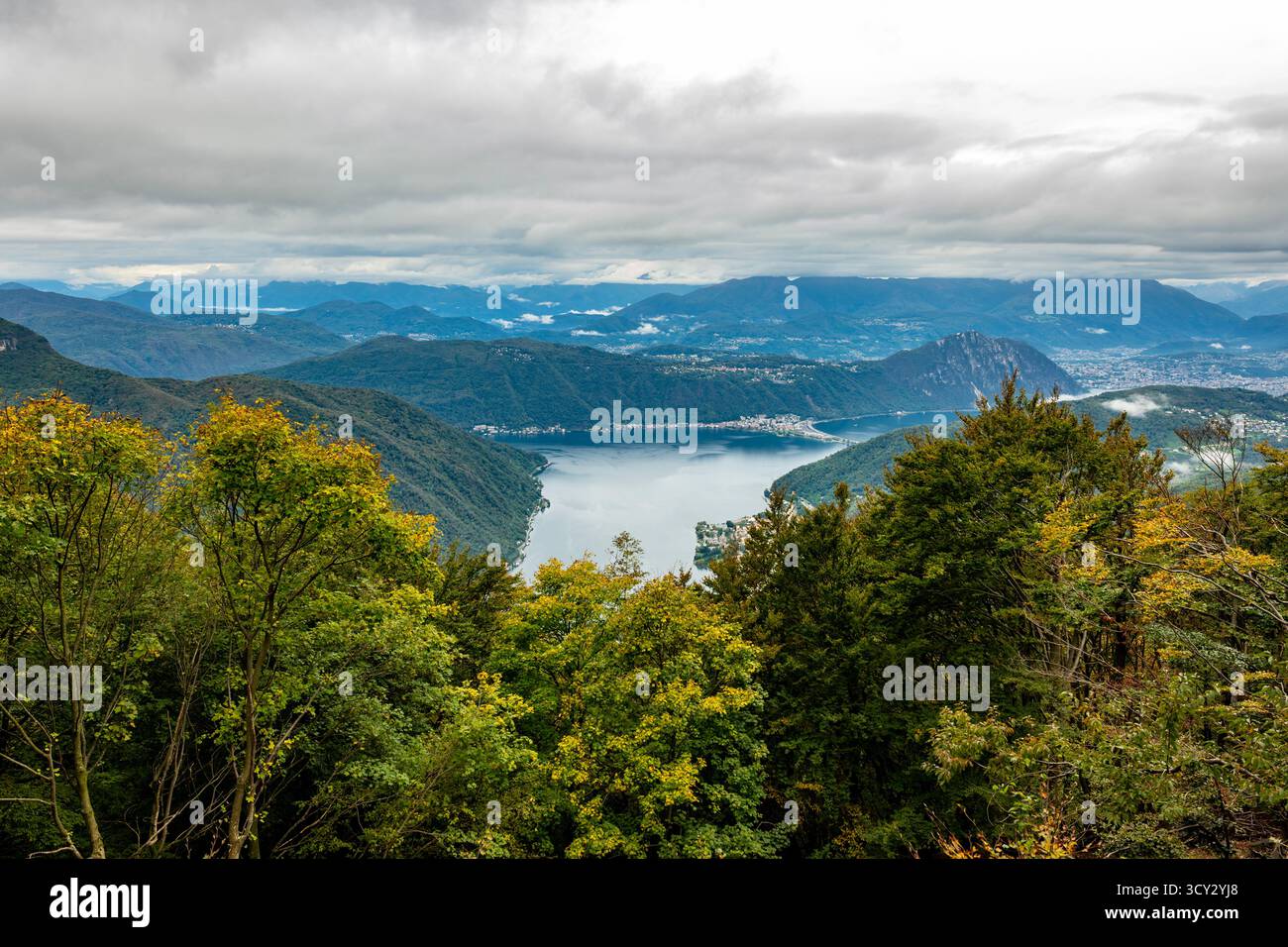 Beautiful Aerial View over City and Lake Lugano and Swiss Alps with Clouds in a Cloudy Day in Autumn in Lugano, Ticino, Switzerland. *** Local Caption Stock Photo
