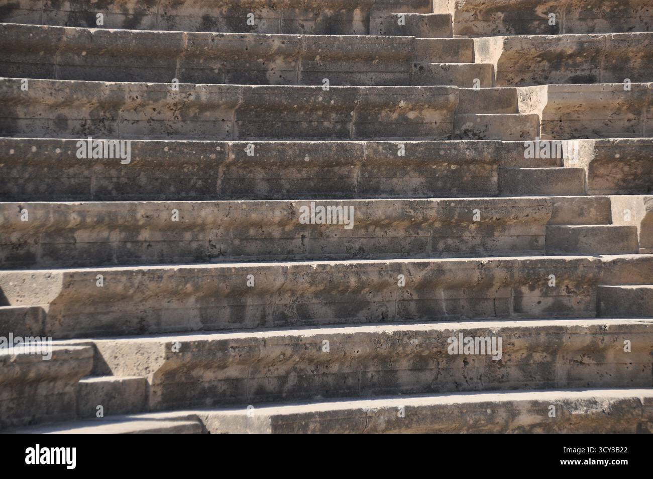 The weathered stone steps form a classic amphitheater structure, bathed ...