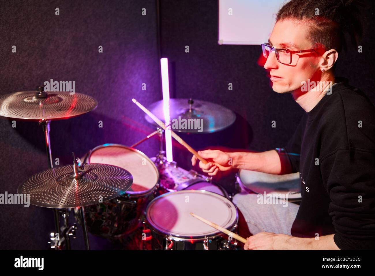 Energetic drummer performing in a studio with colorful lights Stock Photo