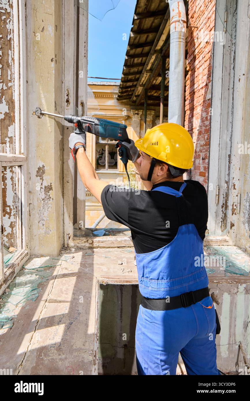 Construction worker repairing window frames in an old building Stock Photo