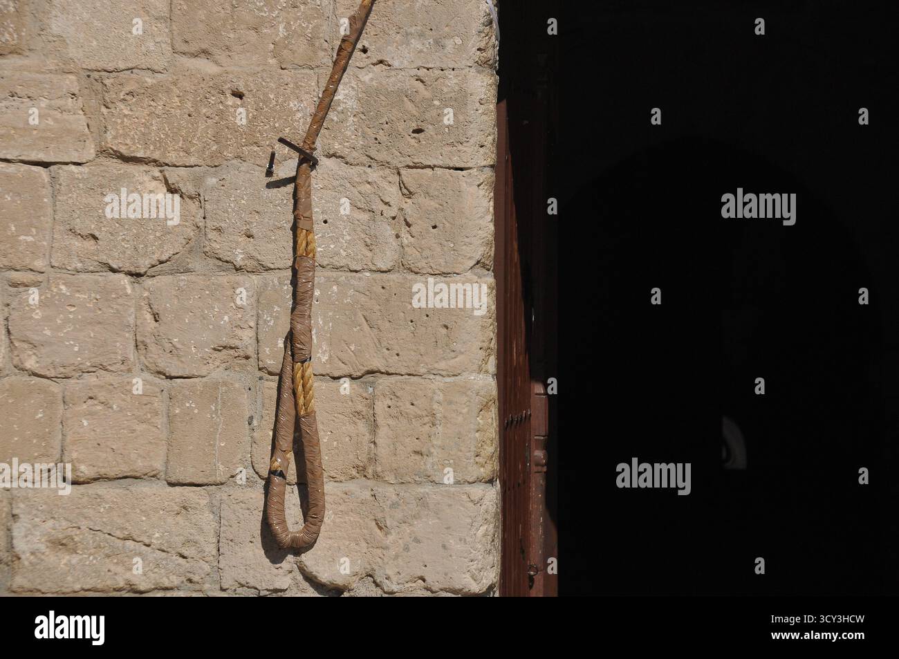 A weathered rope is tied to a stone wall, showing signs of age and use ...