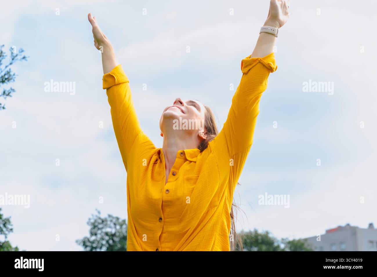 Happy young woman outdoors raising arms celebrating freedom and success Stock Photo