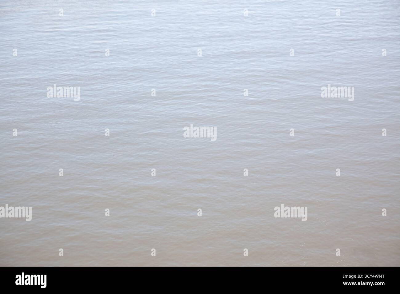 The surface of the river reflects a smooth and gentle texture, with light ripples moving slowly. The scene captures the essence of tranquility on a su Stock Photo