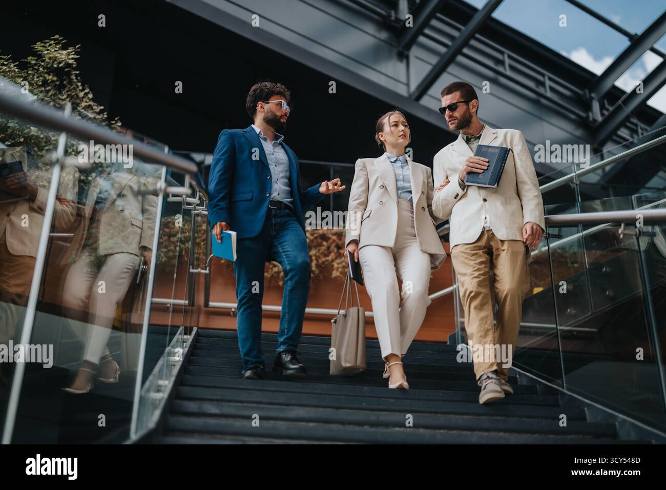 Three business professionals walking down stairs in a modern building Stock Photo