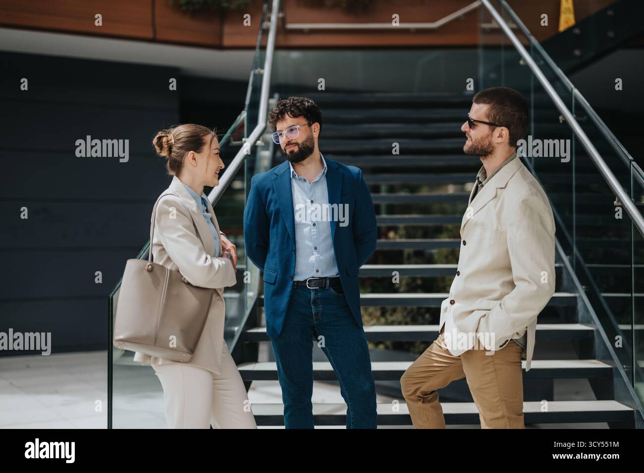 Three professionals having a casual conversation outdoors near a staircase Stock Photo